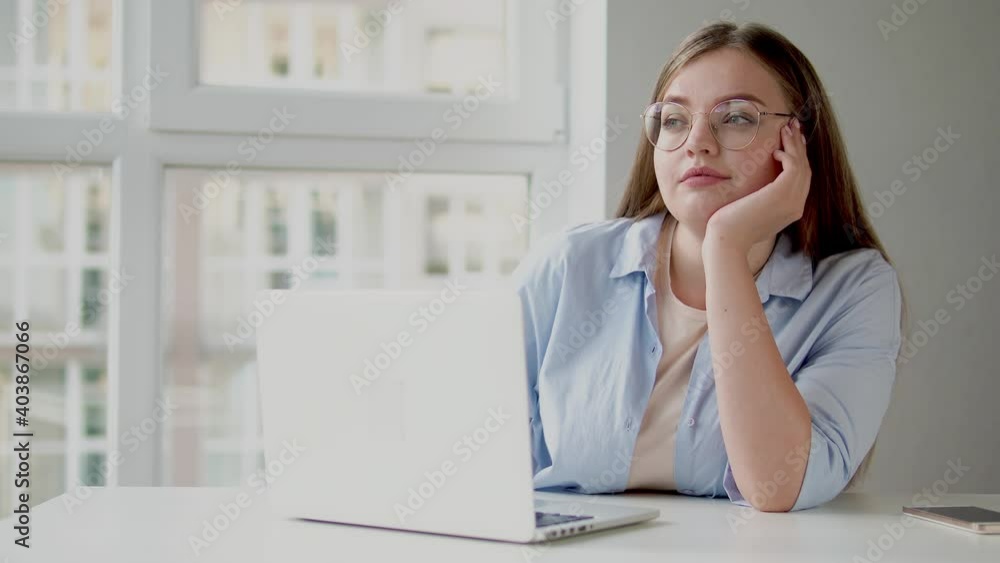 Dreamy beautiful woman sitting in workplace with laptop, working on article Dreamy beautiful woman sitting in workplace with laptop, working on article