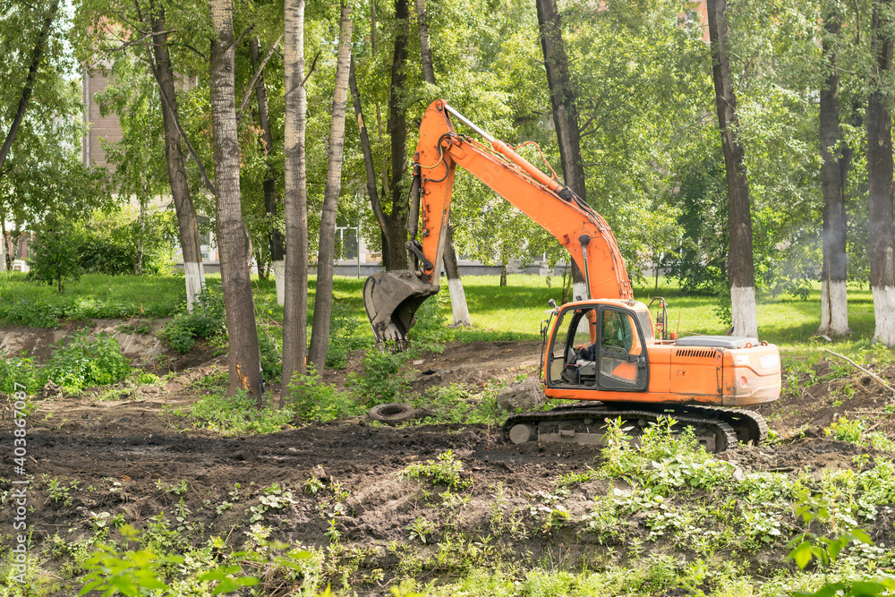 Excavator in the city among the trees. Excavator in the city among the trees.