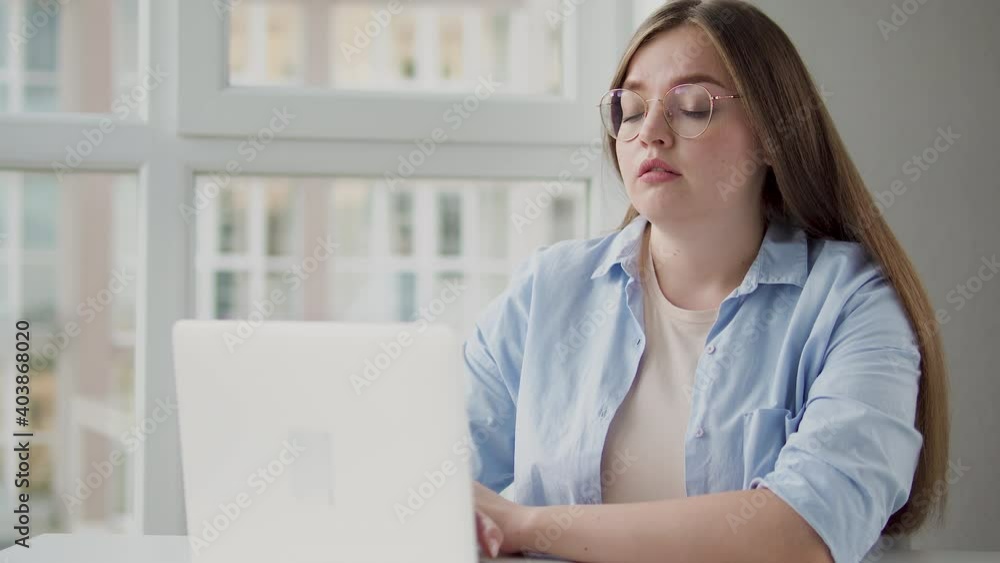 Sleepy young woman in eyeglasses working on laptop, freelance project, deadline Sleepy young woman in eyeglasses working on laptop, freelance project, deadline