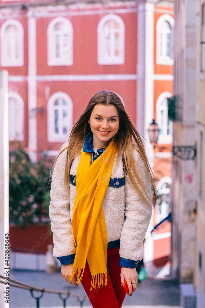 girl in stylish clothes looks at the camera and walks the street