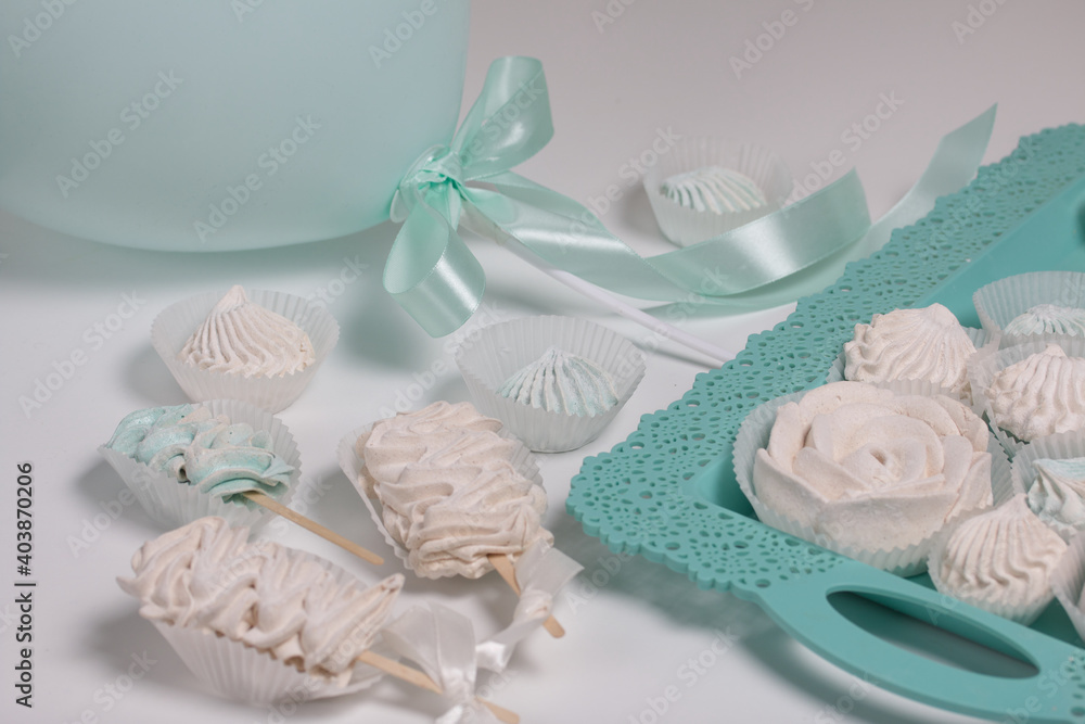 Zephyr on a stick. Marshmallows of different shapes and shades. Close-up shot. On a white table top and a turquoise tray. Zephyr on a stick. Marshmallows of different shapes and shades. Close-up shot. On a white table top and a turquoise tray.