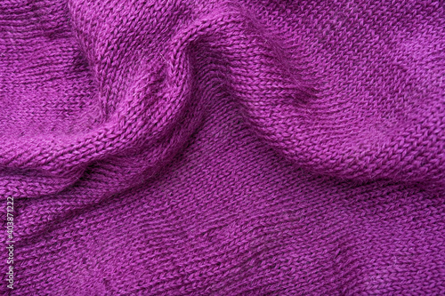 Woolen crumpled purple fabric as background close-up, violet knitted clothes, crochet and knitting photo