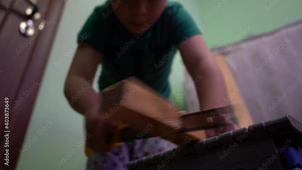 A child is sawing a wooden board with a hacksaw. A child is sawing a wooden board with a hacksaw.