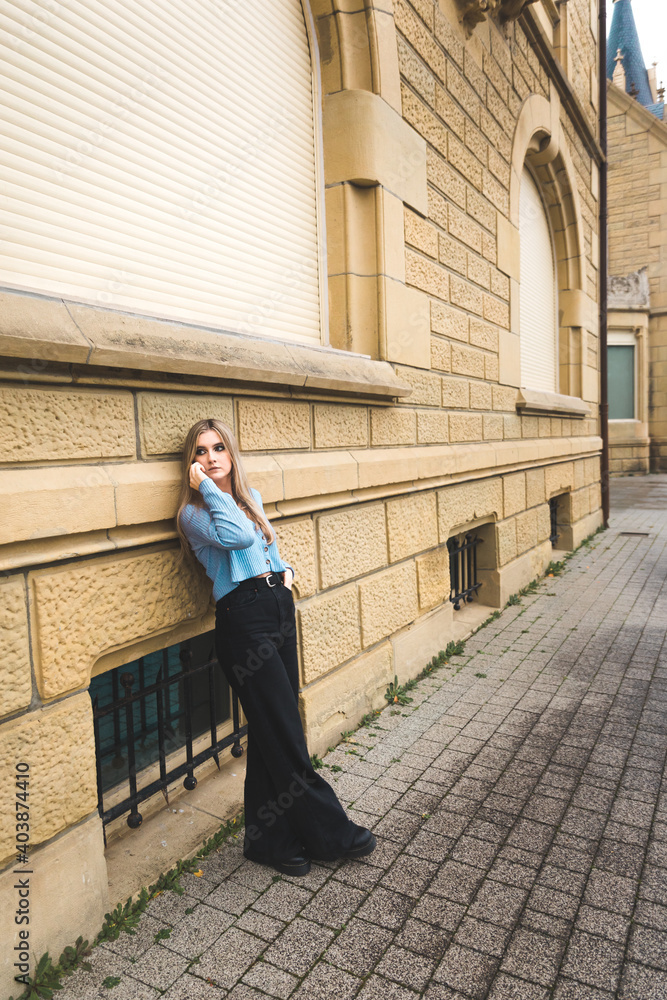 Young blonde woman taking by mobile phone on the street