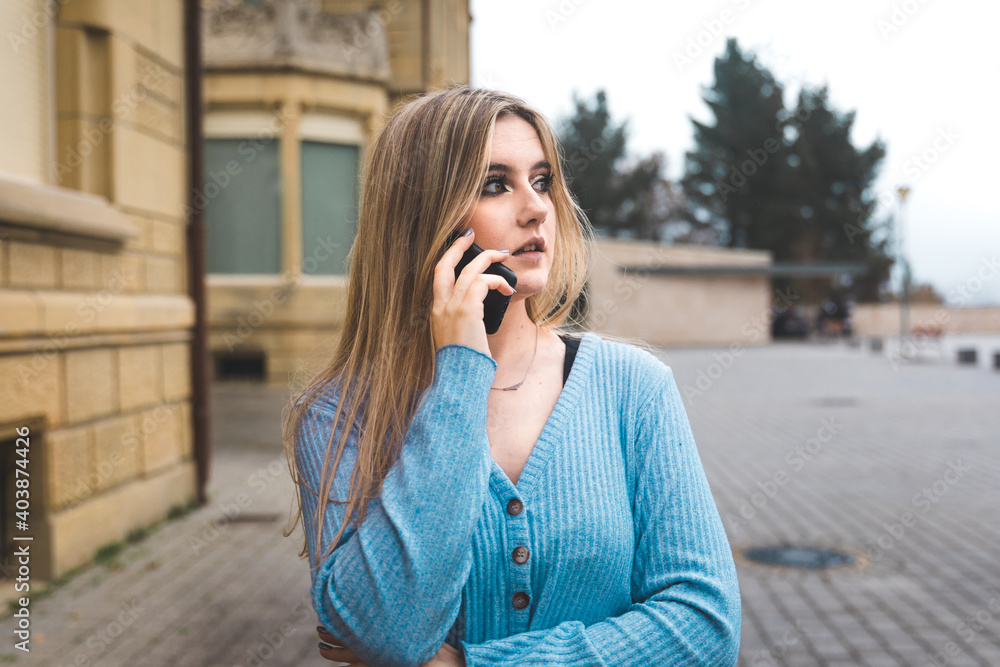Young blonde woman taking by mobile phone on the street Young blonde woman taking by mobile phone on the street