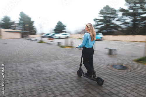 Young blonde woman moving on a e-scooter at the city.