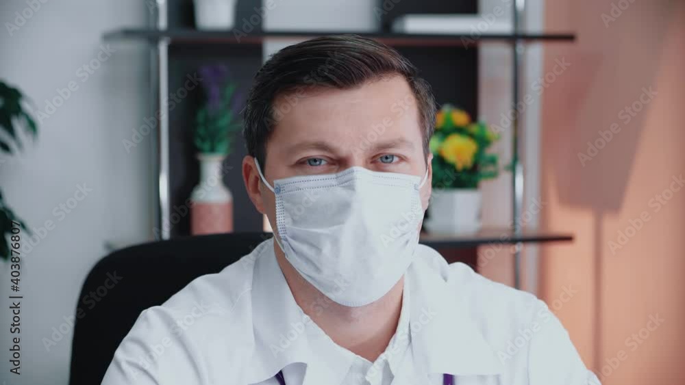 Portrait of a male doctor in a mask sitting in the office. Portrait of a young male Caucasian doctor with a medical facial mask looking at the camera. Medical worker in a protective mask. Portrait of a male doctor in a mask sitting in the office. Portrait of a young male Caucasian doctor with a medical facial mask looking at the camera. Medical worker in a protective mask.
