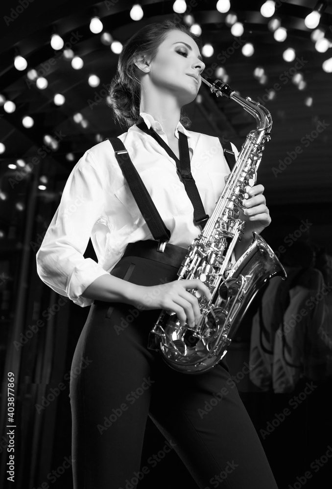 Obraz premium Gorgeous brunette model woman in fashionable formal suit with saxophone