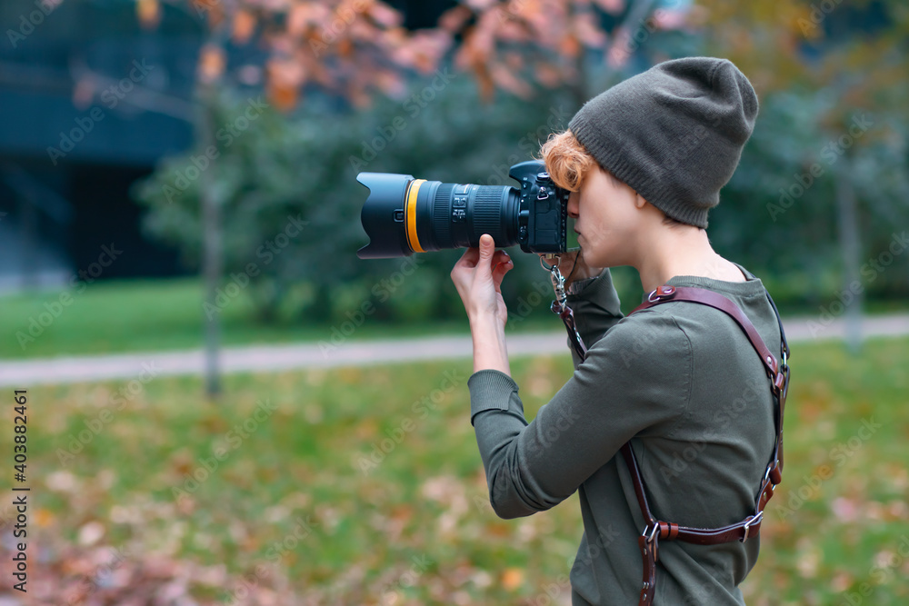 Young woman photographer, Journalist takes pictures on the street, on the street of the park woman holds a camera in her hands.
