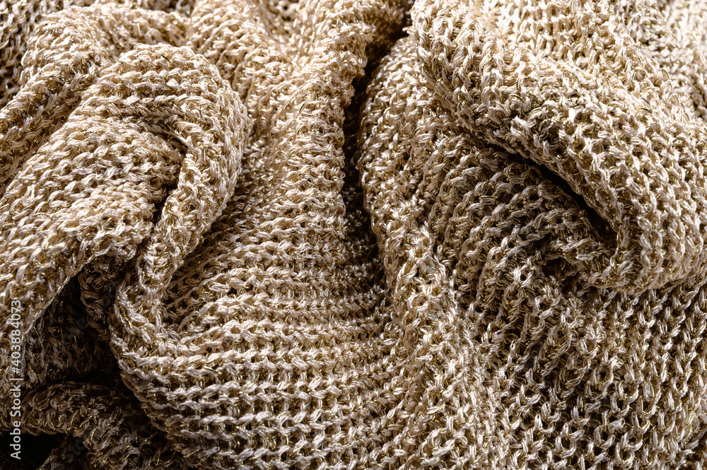 Background of knitted crumpled fabric in gold color close-up. Background of knitted crumpled fabric in gold color close-up.