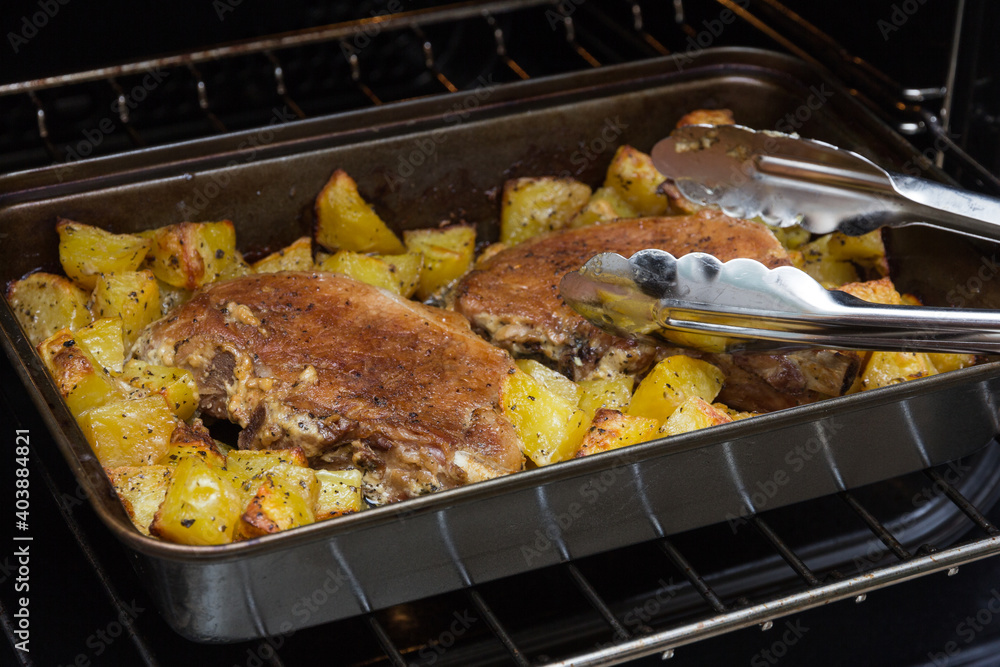 Two pork entrecotes with potatoes baked in the oven. Homemade food in the oven. Baked meat with vegetables. Pork meat in the oven