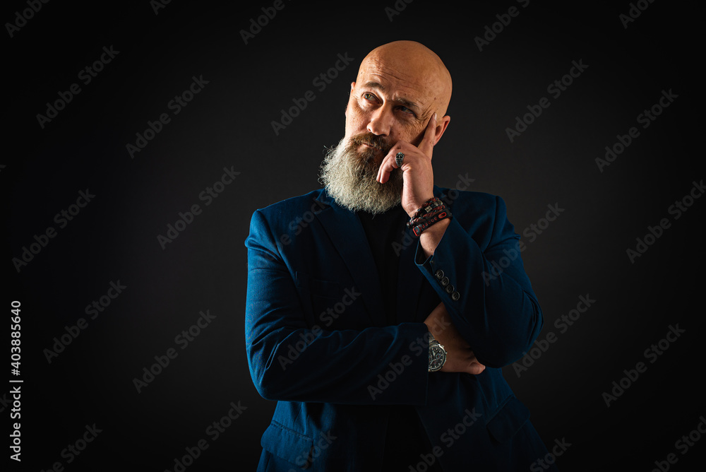 Smiling business man with beard showing man, gesturing with hands, showing something, isolated on dark background. Low key. The portrait is emotional Smiling business man with beard showing man, gesturing with hands, showing something, isolated on dark background. Low key. The portrait is emotional