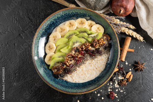 Oatmeal with chia seeds, banana, kiwi, walnuts and dried cranberries. A classic morning hot healthy breakfast of cereal porridge with fruits, nuts and dried fruits.