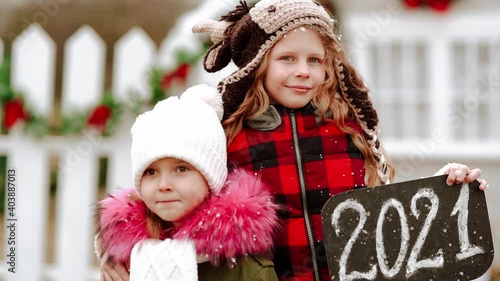 Two sisters posing with name plate with 2021 symbol . Slow mo. photo