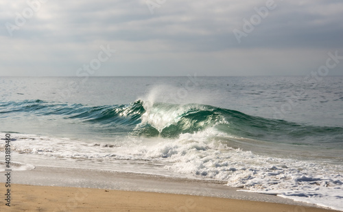 Ocean wave curling over on a sandy shore