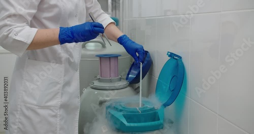 Young woman laboratory assistant in mask is working in DNA laboratory with cryostat photo