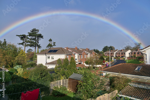 View of houses and gardens in southern Dublin with beautiful rainbow captured from a window during coronavirus lockdown, Dublin, Ireland. Wide angle view © Romio Shots