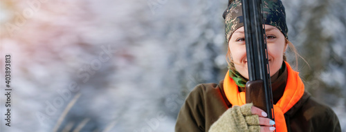 Fotografia A young beautiful hunter woman on hunt in forest with rifle on the shoulder