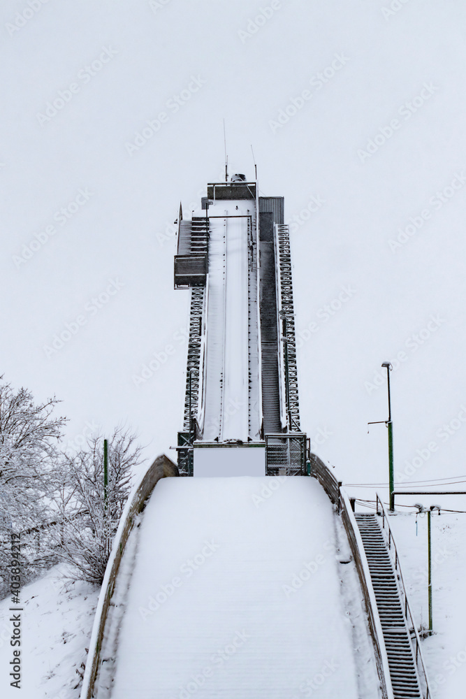 Straight view from under an empty ski jump tower covered with snow in winter - obrazy, fototapety, plakaty 