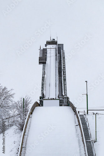 Straight view from under an empty ski jump tower covered with snow in winter