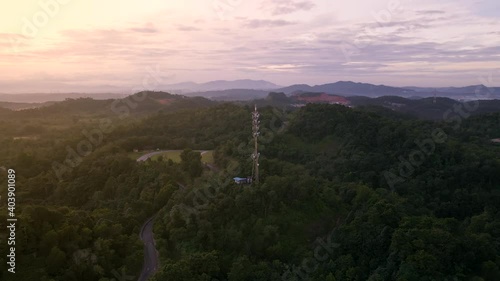 4K UHD Cinematic Aerial footage circle view of 5G Communication tower during morning sunrise with clouds, mists and fog