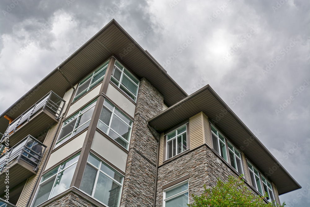 Top of residential building with stone texture wall on cloudy sky background.