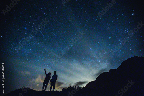 Silhouette of elderly couple on the hill.  Stargazing at Oahu island, Hawaii. Starry night sky, Milky Way galaxy astrophotography.