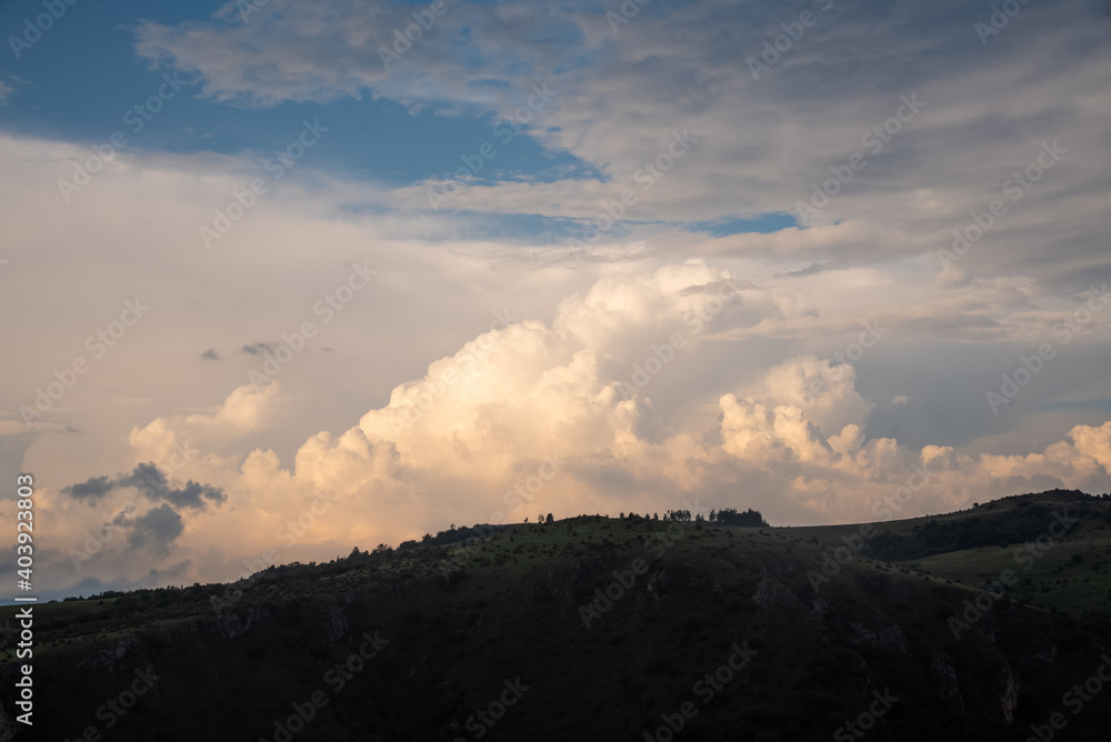Obraz premium Scenic canyon view of meanders on the river Uvac, on the Zlatar Mountain with beautiful sunset with dramatic and fluffy white clouds and sky in background. Uvac is a special nature reserve in Serbia.