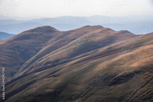 Beautiful mountain landscape of green and yellow meadows on Balkan Mountains in Serbia.Sunlit highlands and grasslands of Old mountain with distant peaks.Hiking trail for the highest peak Midzor 2169m