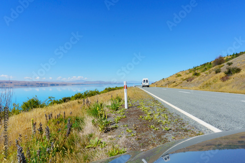 On highway around Lake Pukaki reflection in car bonnet of road ahead in view of turquoise water photo