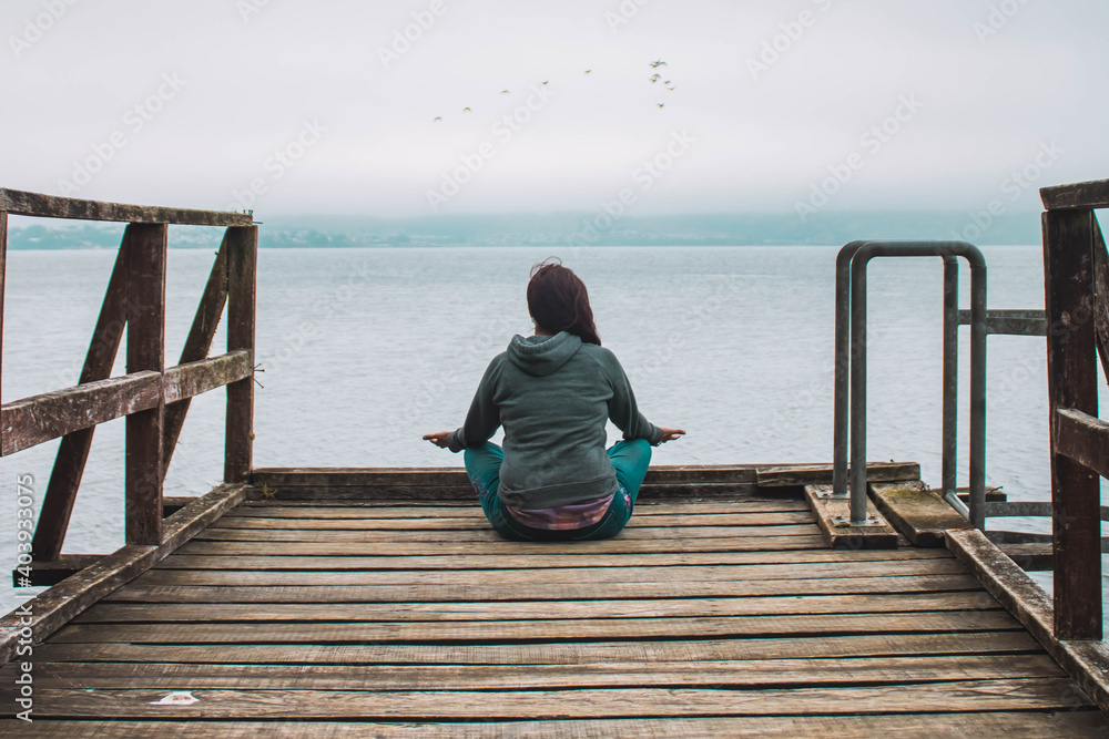 young woman meditating in front of the sea