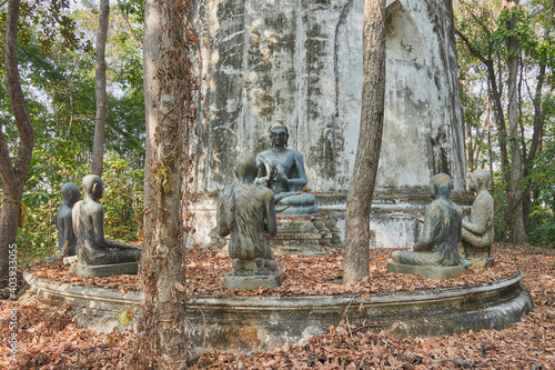 Phayao, Thailand - Dec 6, 2020: Front Buddha Statue Giving The First Sermon with 5 Disciples of The Buddha on Forest Background in Wat Analayo Temple photo