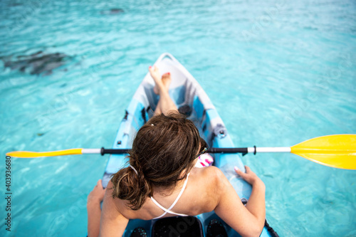 Woman relaxes on a kayak over the turquoise ocean water at tropical island Moorea in French Polynesia