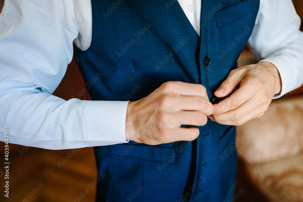 Man is buttoning his vest. close-up. Perfect to the last detail. Modern businessman. Fashion shot of a handsome young man in elegant classic suit. Men's beauty, fashion.