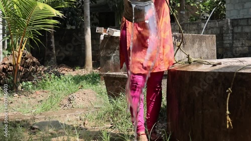 Indian woman fetching , drawing water from well by hand, pouring fresh pure drinking mineral water splashing , fresh water resource 4K slow motion video footage Kerala India in rural Indian village 