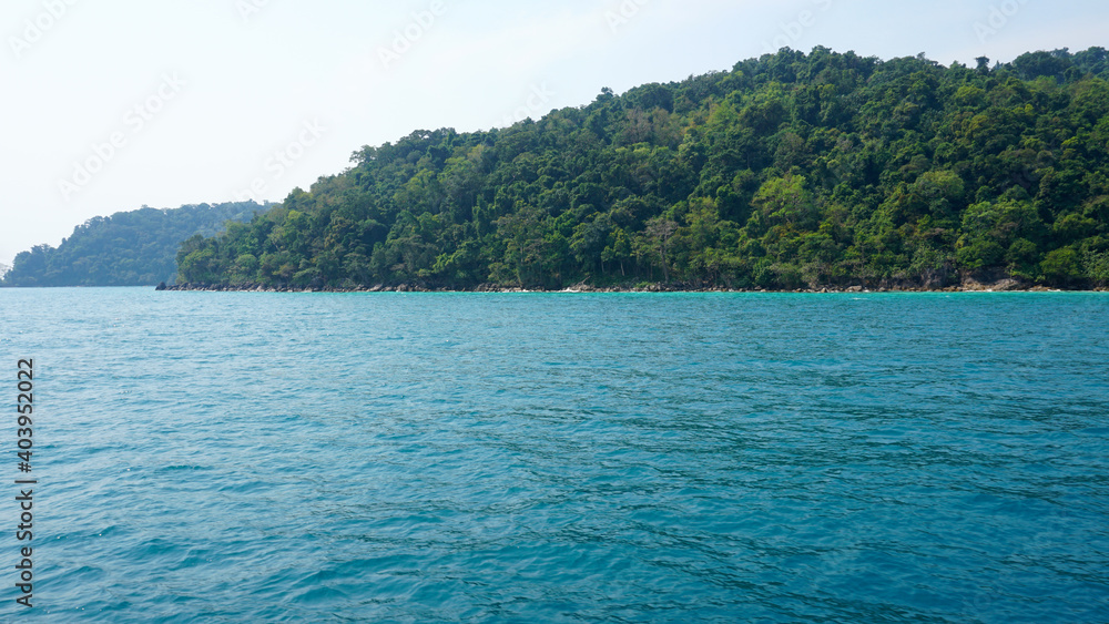 Travel by sea in Thailand by ship. View of the open ocean, green Islands and gray sky in smog. Green water with waves. Sailing between the Islands. Ship from different sides: stern, bow, rope, anchor.