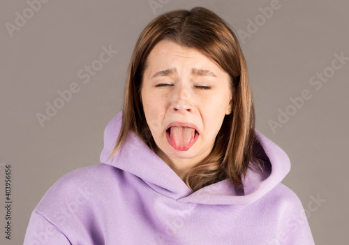 Fotografia Headshot of naughty girl of European appearance sticking out tongue, trying to tease someone, looking immature and offensive, all her appearance expressing rudeness and disgust