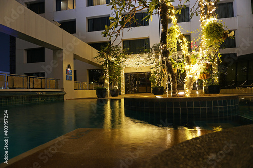 Night pool with beautiful lighting and wood. Romantic mood in hotels. The water reflects the light of the lights that are located on the tree in the middle of the pool and at the entrance. Thailand photo