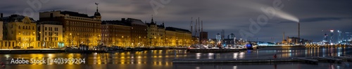 A beautiful panorama cityscape of downtown Helsinki waterfront. Colorful sky casting reflections on the frozen water surface.