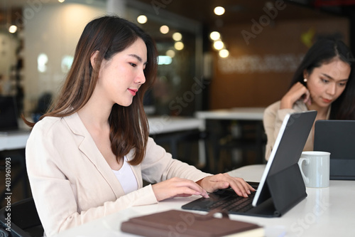 Two young businesswoman using tablet computer and working together in office. © Prathankarnpap