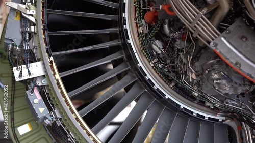 Fan blades windmilling on a turbine engine of a commercial aircraft viewed from underneath an open cowl.