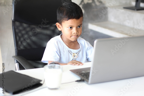 Asian boy kid sitting at table with laptop and preparing to school. Online education concept. Online video call conference class lesson study.