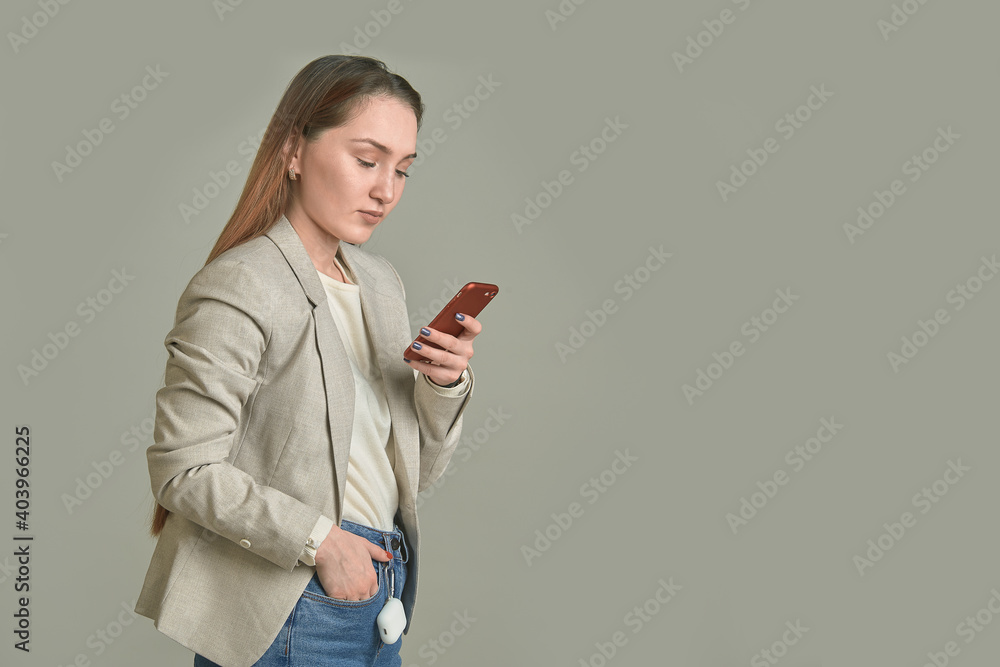 Business woman with a phone in her hands on a gray background Business woman with a phone in her hands on a gray background