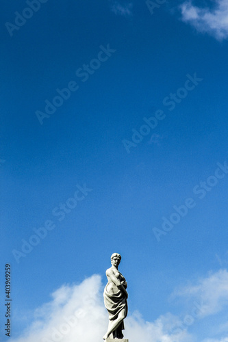 Blue Modesty. Great Statue on top of a building in Russia, Saint Petersburg. looking down on people while garbing the garment. smooth blueness in the sky.