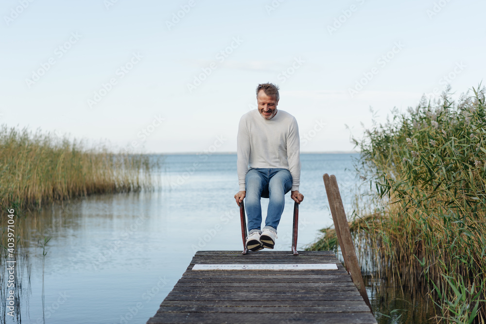 Smiling fit active man playing on a wooden jetty Smiling fit active man playing on a wooden jetty