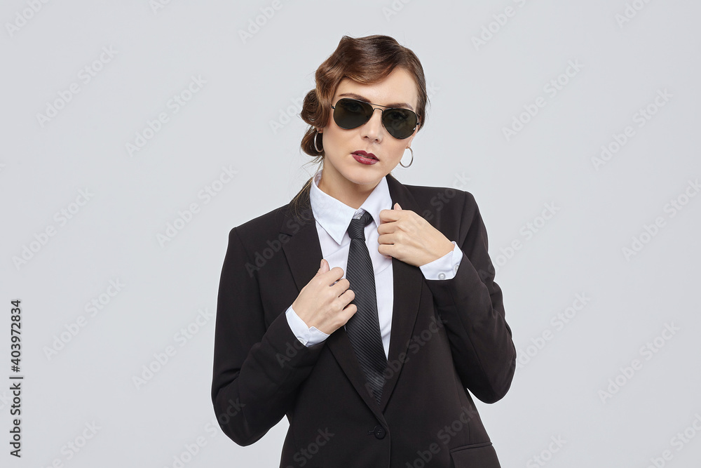 attractive woman with a retro hairstyle poses in a men's suit and sunglasses attractive woman with a retro hairstyle poses in a men's suit and sunglasses
