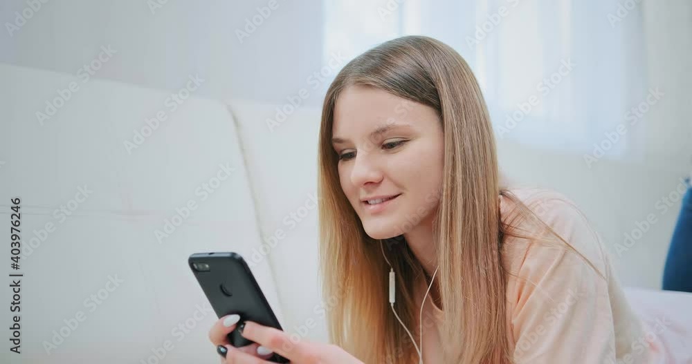 Young blonde in white headphones talks on video call and verifies different orders in internet shop at pandemic isolation