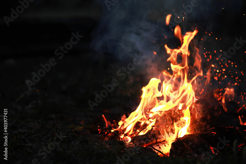 Burning red hot sparks fly from big fire. Burning coals  flaming particles flying off against black background.