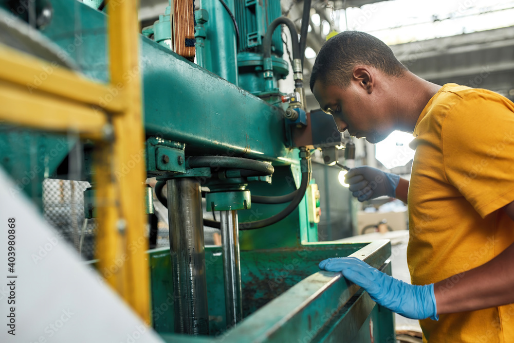 Young man managing compression machine on waste station Young man managing compression machine on waste station