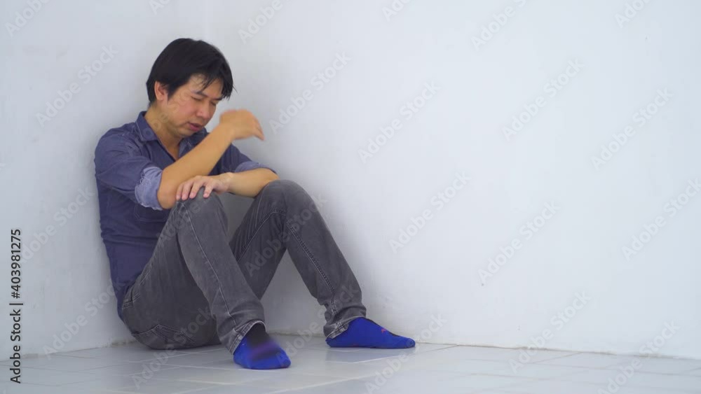 Sad upset asian businessman sitting in corner leaning against the wall in old condo, Domestic violence, family problems, Stress, violence, The concept of depression and suicide Sad upset asian businessman sitting in corner leaning against the wall in old condo, Domestic violence, family problems, Stress, violence, The concept of depression and suicide
